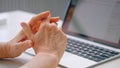 Old woman company manager holds wrinkly hands over keyboard and types against blurred table with light reflections at home Royalty Free Stock Photo