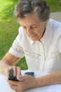 An old woman in dialling a telephone number on a smartphone Royalty Free Stock Photo