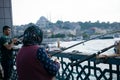 Old woman fishing on Galata bridge. Vacation in Istanbul