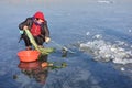 An old woman is fishing through an ice hole