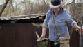 Old woman gardener fulling watering pot from barrel in garden