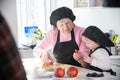 An old woman giving a piece of apple to a little girl in the kitchen Royalty Free Stock Photo