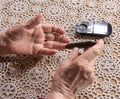 Old woman with glucometer checking blood sugar level Royalty Free Stock Photo