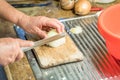 Old woman granny cutting onion in kitchen with knife and wooden board next to sink and red plastic bowl, Germany Royalty Free Stock Photo