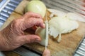 Old woman granny cutting onion in kitchen with knife and wooden board next to sink and red plastic bowl, Germany Royalty Free Stock Photo