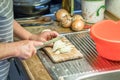 Old woman granny cutting onion in kitchen with knife and wooden board next to sink and red plastic bowl, Germany Royalty Free Stock Photo