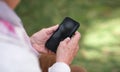 Old woman hands using smartphone texting sending messages on mobile phone outdoors Royalty Free Stock Photo