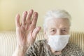 Old woman with health mask making stop sign with wrinkled hand