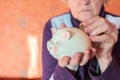 Old woman holding piggy bank and coins Royalty Free Stock Photo