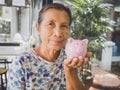 Old woman holding Pink piggy bank. Saving money for future plan and retirement fund concept Royalty Free Stock Photo