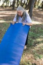 Old woman holding yoga mat and preparing to practice yoga or meditation outdoors on park. Happy mature woman with Royalty Free Stock Photo