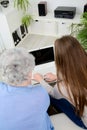 Old woman at home with cheerful young girl spending time together with laptop computer Royalty Free Stock Photo