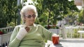 Old woman with injured hand drinking coffee outdoor Royalty Free Stock Photo