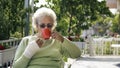 old woman with injured hand drinking coffee tea outdoor Royalty Free Stock Photo