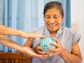 Old woman looking scared trying to protect her blue piggy bank from Financial fraud, Saving money for future plan and retirement Royalty Free Stock Photo