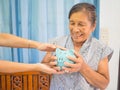Old woman looking scared trying to protect her blue piggy bank from Financial fraud, Saving money for future plan and retirement Royalty Free Stock Photo