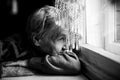 An old woman looking at the window. Black and white photography.