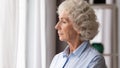 Old woman looking in window thinking lost in sad thoughts Royalty Free Stock Photo