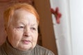 Old woman looks out the window. Portrait.