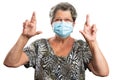 Old woman making good luck gesture fingers crossed wearing mask