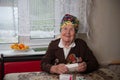 old woman with medals sits at a table and examines medicine boxes