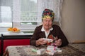 Old woman with medals sits at a table and examines medicine boxes