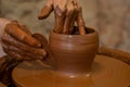 Old woman potter working on Potter wheel making a clay pot. Master forming the clay with her hands creating pot in a Royalty Free Stock Photo