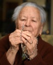 Old woman praying and holding silver rosary Royalty Free Stock Photo