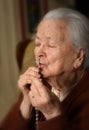 Old woman praying and holding silver rosary Royalty Free Stock Photo