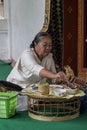 Old woman preparing food at the door of a Buddhist temple