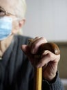 An old woman with a protective face mask holds a stick handle indoors  quarantine Royalty Free Stock Photo