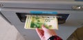 Old woman pulls banknotes Israeli shekels from atm