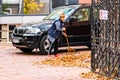 Old woman raking fallen leaves in the courtyard, senior woman gardening during autumn season, cleaning the yard in Bucharest,