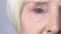 Old woman with red eyes looking into camera, allergy to cosmetics, lacrimation