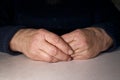 The old woman`s clasped hands lie on the table. Wrinkles on the hands. Loneliness of the elderly