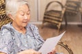 Old woman seated reading carefully a document or terms of a insurance. Old obaasan (grandma), japanese descendant.