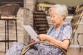 Old woman seated reading carefully a document or terms of a insurance. Old obaasan (grandma), japanese descendant. Royalty Free Stock Photo