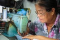 Old woman sews on the sewing machine in the street