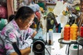 Old woman sews on the sewing machine in the street