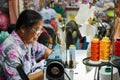 Old woman sews on the sewing machine in the street