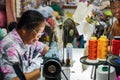 Old woman sews on the sewing machine in the street