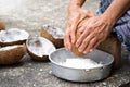 Old woman sit on coconut grater and grate coconut