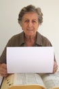 An old woman sits close to the big explanatory encyclopaedia