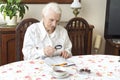 The old woman sits at a table with a newspaper. Royalty Free Stock Photo