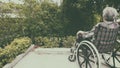 Old woman sitting alone in a wheelchair out in the garden. Royalty Free Stock Photo