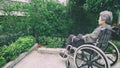 Old woman sitting alone in a wheelchair out in the garden. Royalty Free Stock Photo