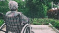 Old woman sitting alone in a wheelchair out in the garden. Royalty Free Stock Photo