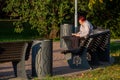 An old woman sitting on the bench read the book in the garden. A people resting in the park.