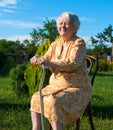 Old woman sitting on a chair with a cane Royalty Free Stock Photo