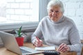 An old woman is sitting at the table in front of laptop Royalty Free Stock Photo